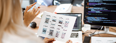 Website wireframes with developer's laptop in background with code on screen.